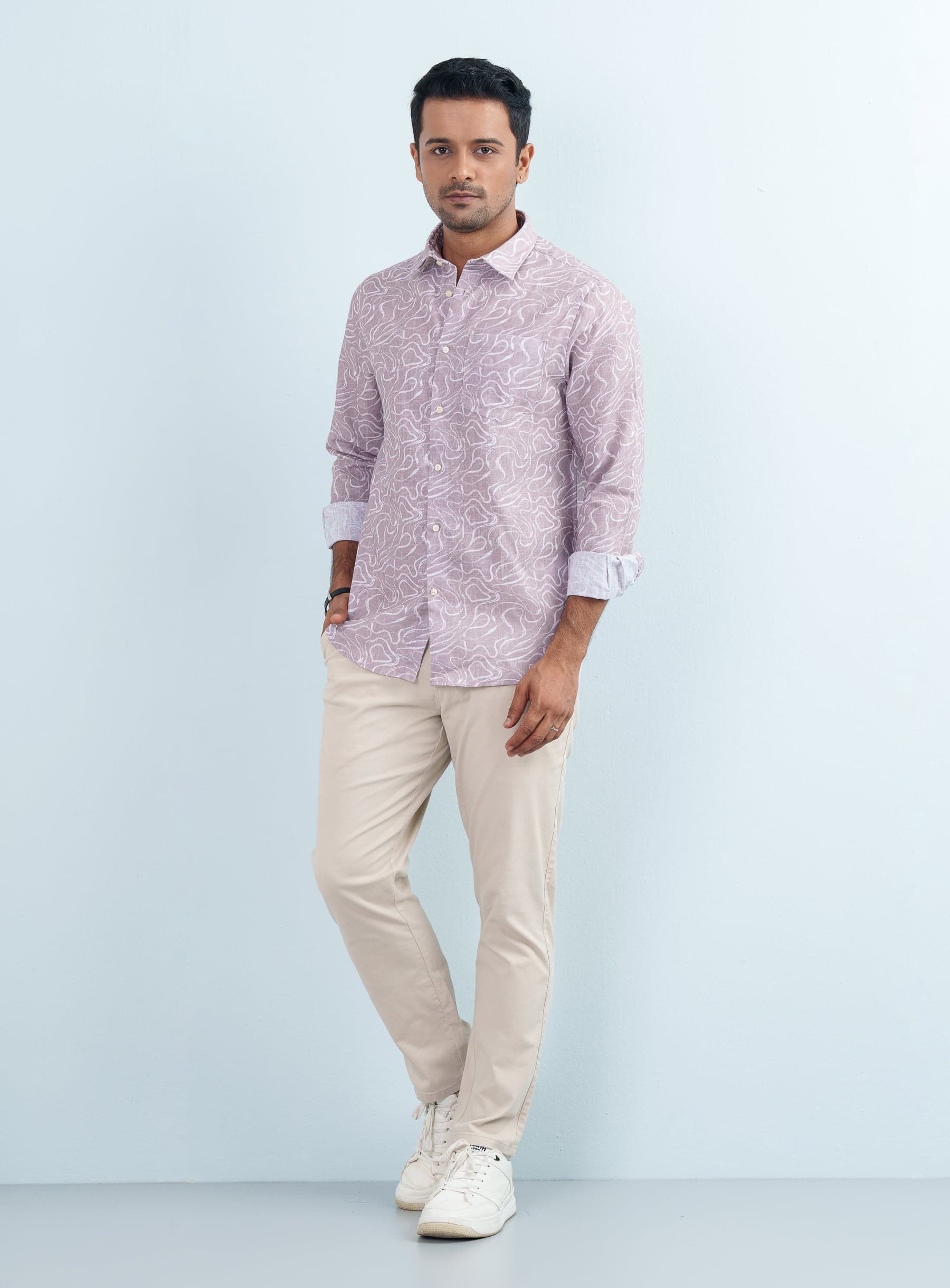 Full-length view of a man modeling a mauve abstract print casual shirt full sleeve with beige chinos.