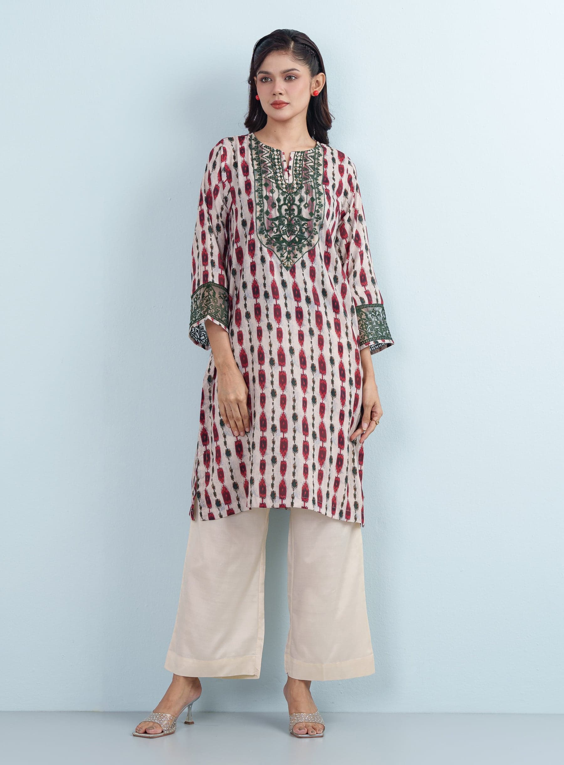 Full-length studio shot of a model wearing a beige and red Ikat printed cotton women's two piece outfit with relaxed wide trousers.