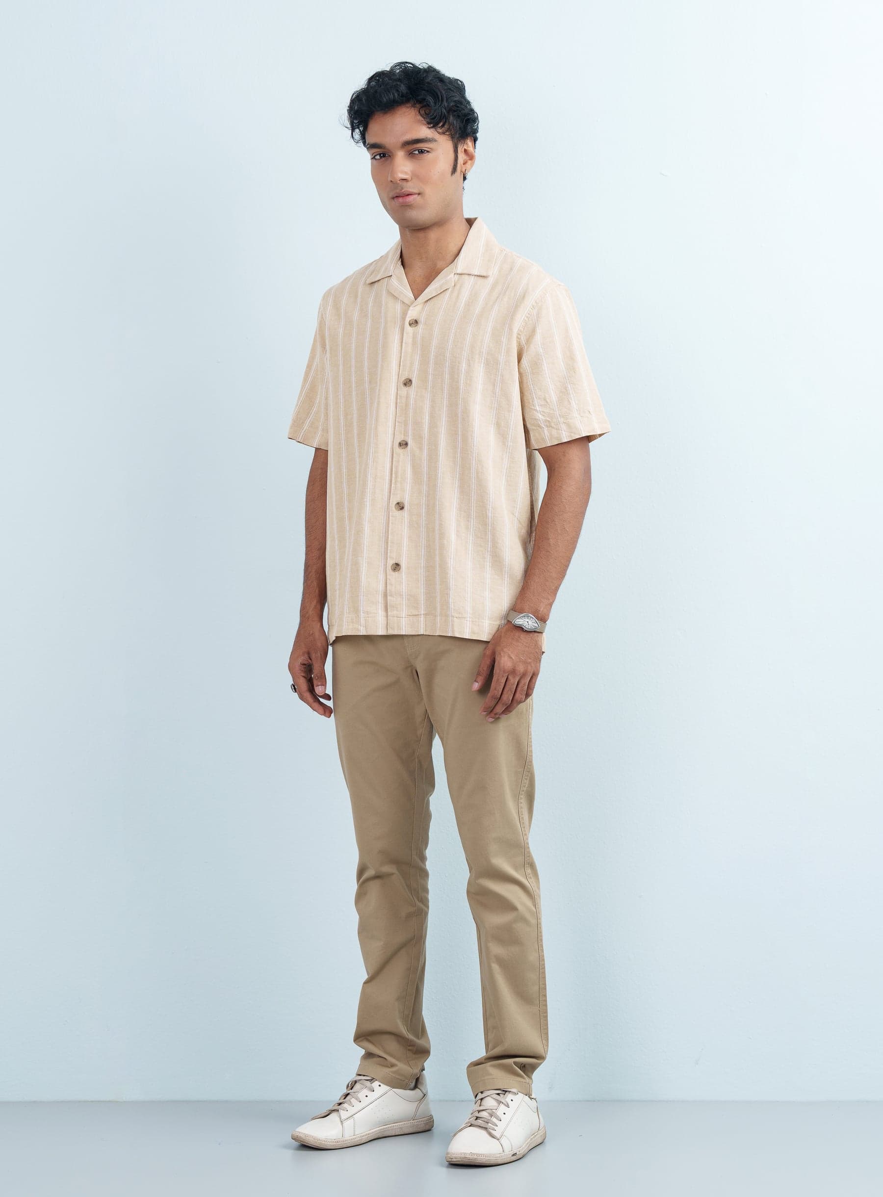 Full body view of a man styling a Beige Striped Cuban Collar Casual Shirt Half Sleeve with khaki pants.