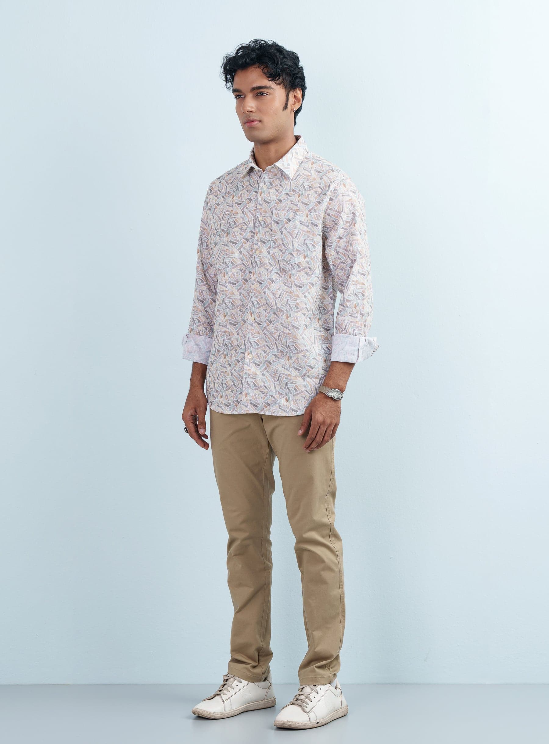 Full length studio photograph of a model wearing a men's Geometric Abstract Print Casual Shirt with beige trousers and white sneakers.