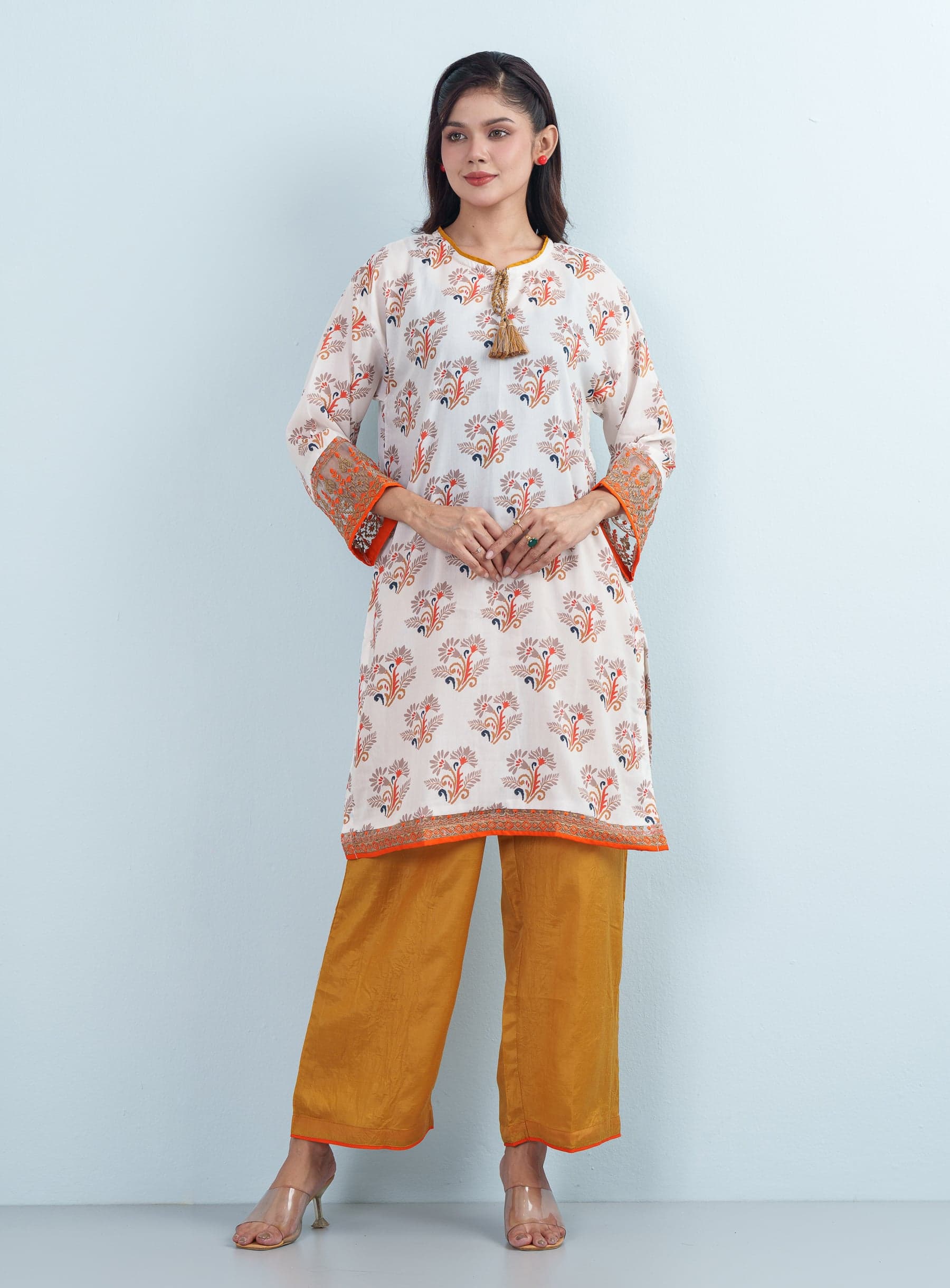 Full-length studio profile of a model presenting an Soft Ivory floral cotton women's two piece set with mustard wide-leg trousers.