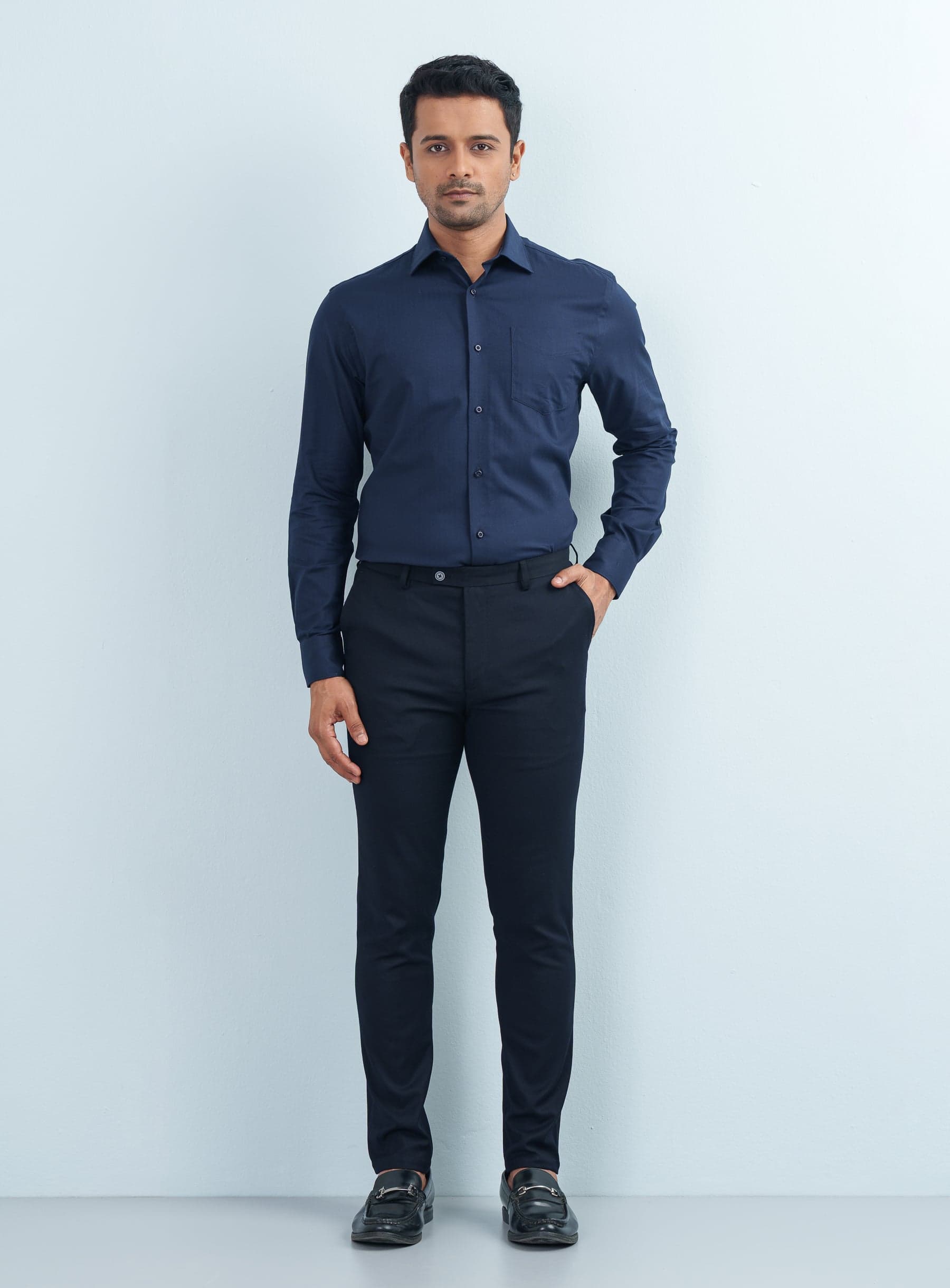Full-length studio shot of a model wearing a navy blue textured formal shirt and dark pants