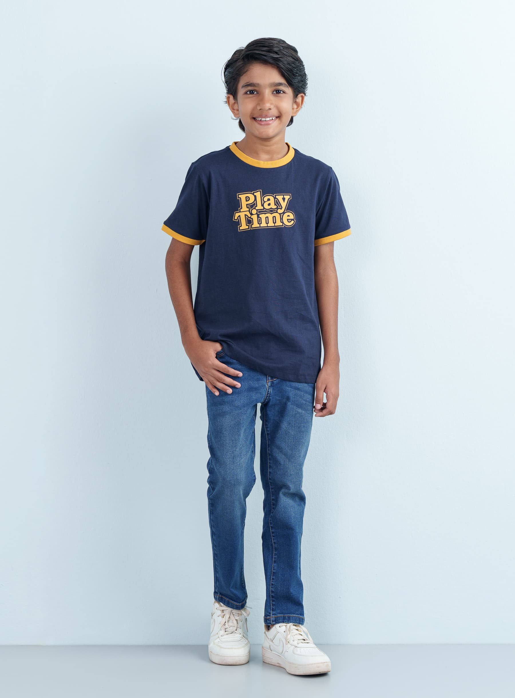 Full-length front view of a smiling young boy wearing a navy blue cotton ringer T Shirt Half featuring "Play Time" graphic text and casual blue jeans.