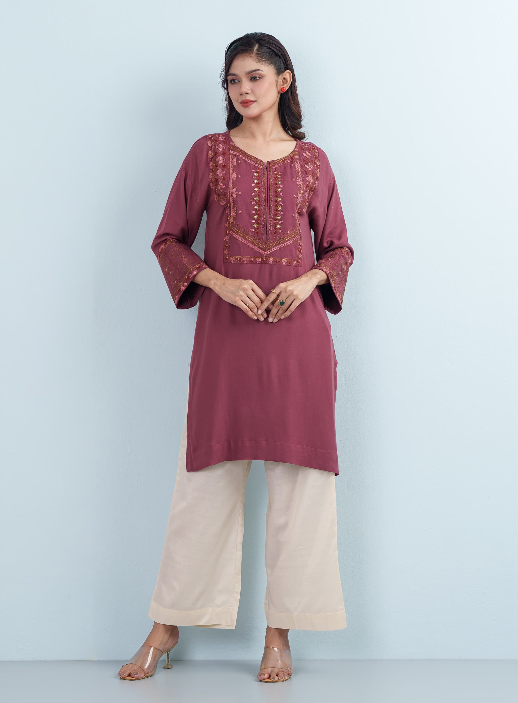 Elegant studio portrait of a woman wearing a deep mauve embroidered Tops long sleve tunic looking slightly to the side.